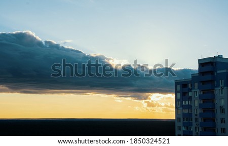 clouds and orange sunset, side view of a high-rise residential building. building site over sunset stormy sky. grunge filter photo	