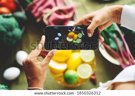 Big table with a lot of delicious meals and plates. Fruits and vegetables. Woman's hands with phone taking food photo