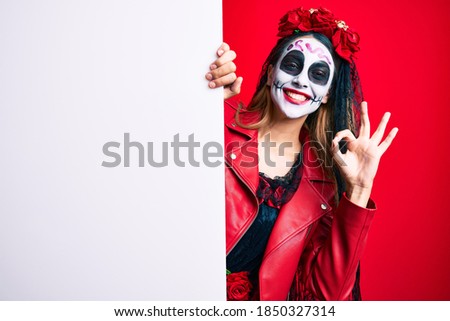Woman wearing day of the dead costume holding blank empty banner doing ok sign with fingers, smiling friendly gesturing excellent symbol 