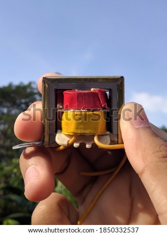 photo of a hand holding a used tv booster transformer, electronic equipment
