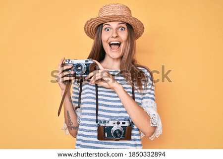 Beautiful caucasian tourist woman holding vintage camera celebrating crazy and amazed for success with open eyes screaming excited. 