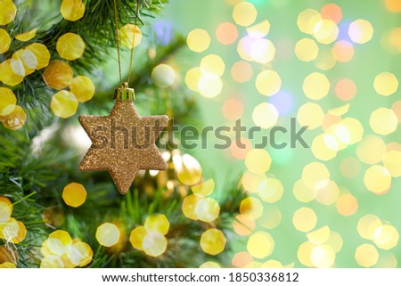 Christmas decoration golden twinkling star on a branch of a christmas tree, christmas tree toy, sparkling shiny background copy space design