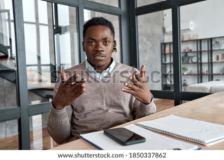 African business man, coach, executive wearing headset talking to camera conference video calling, giving webinar, online class, distance teaching or working at home office, web cam view. Headshot. Royalty-Free Stock Photo #1850337862