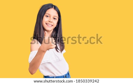 Beautiful child girl wearing casual clothes doing happy thumbs up gesture with hand. approving expression looking at the camera showing success. 