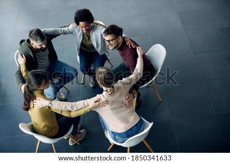 High angle view of group of supportive people sitting in a circle and embracing each other during group therapy. Copy space.  Royalty-Free Stock Photo #1850341633
