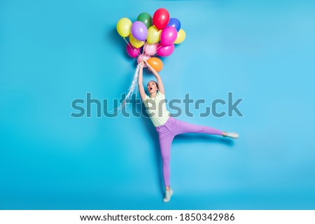 Full length body size photo of girl keeping pile of air colorful balloons amazed windy weather isolated on vivid blue color background