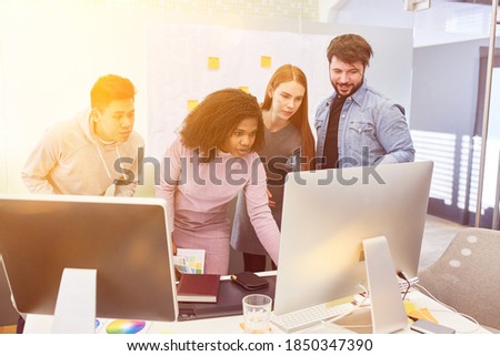 Team of web designers stands together in the office on the computer working together