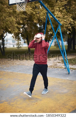 Athletic sporty man training in hoodie sweatshirt in urban city park / basketball court.