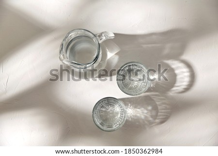 drink and glassware concept - two glasses and jug with water on white background with shadows Royalty-Free Stock Photo #1850362984