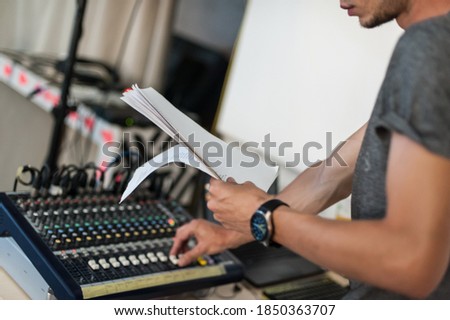 Behind the scene. Sound technician adjusting sound elements for the theatrical performance and looking at script