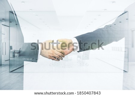 Handshake of two businessmen on modern furnished office interior background, deal and partnership concept. Multiexposure