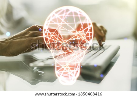 Creative idea concept with light bulb illustration and hands typing on laptop on background. Multiexposure