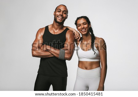 Cheerful male and female athlete standing together at gym. Smiling woman standing with her hand on shoulder of male friend. Royalty-Free Stock Photo #1850415481