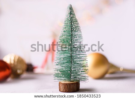New Year's card on a bright background. Little eve tree, Christmas tree balls, lights. Merry christmas and happy new year