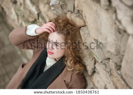 Portrait of a beautiful young woman near a stone wall. Outside. View from above
