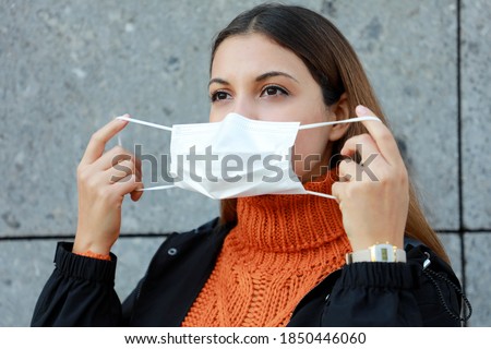Beautiful young woman wearing protective mask in city street Royalty-Free Stock Photo #1850446060