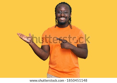 Handsome young african american man wearing casual clothes amazed and smiling to the camera while presenting with hand and pointing with finger. 