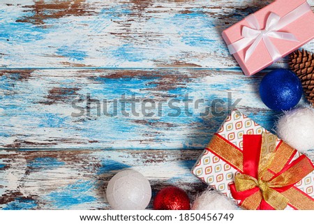 Two boxes tied with ribbons with Christmas balls and a pine cone on the background of boards covered with white and blue paint. A greeting card for Christmas with a place for text.