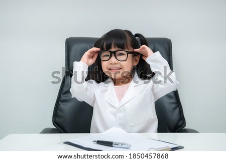 Portrait of cute asian little girl in doctor uniform working on the desk on white background