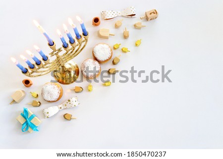 Image of jewish holiday Hanukkah with menorah (traditional Candelabra), donut and wooden dreidel (spinning top)