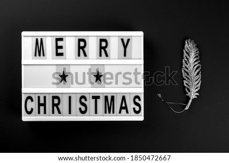 Merry Christmas lettering on lightbox.Festive composition with traditional decoration on a black background.Creative Concept for Greeting Holiday Card. Flat lay top view