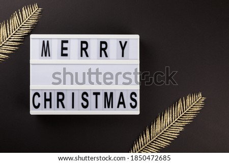 Merry Christmas lettering on lightbox.Festive composition with traditional decoration on a black background.Creative Concept for Greeting Holiday Card. Flat lay top view