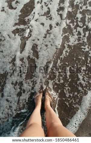 A high angle shot of a person standing on the beach near seafoam