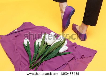 Beautiful female legs are dressed in stylish violet flat shoes. violet sandals on a yellow background.