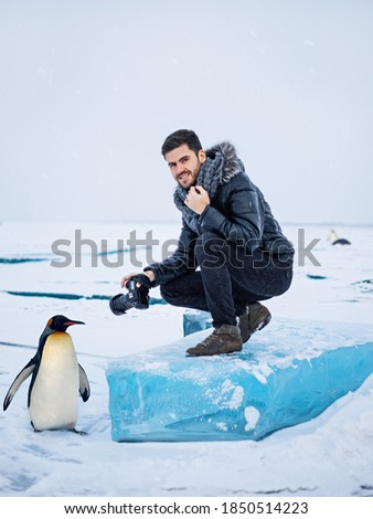 Photographer in the Arctic with photographs of a penguin