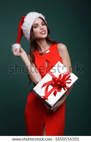 Beautiful young woman, evening makeup stylish dress , brunette, gift boxes red silk bows New Year, Christmas. Fashion photo. Studio Shot. Red and green color. New year's Christmas cap