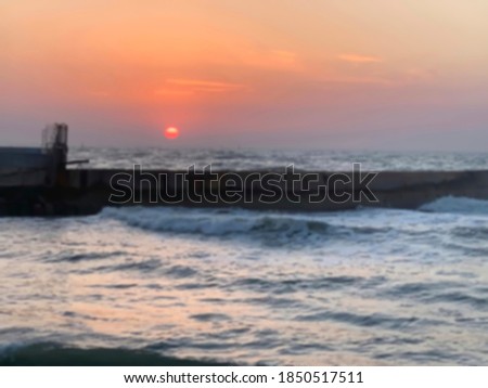 Bright tropical sunset with red sun under the sea surface. Blurred view
