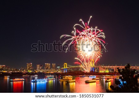 Aerial Skyline of Rainbow Bridge and Symbolic Tokyo Tower at night time with a lot of lighten boats in the river and spectacular winter fireworks.