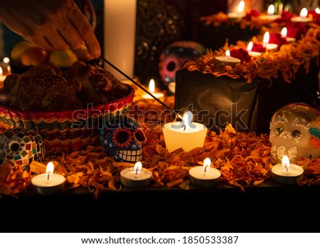 Hand holding incense stick over "ofrenda" for the Day of the Dead Royalty-Free Stock Photo #1850533387
