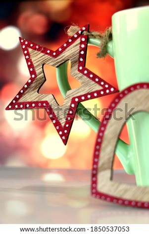 Chistmas wooden star and heart with red and white decoration on a green mug filled with warm winter beverage on golden blurred bokeh background in December during the Holiday Season - cozy family time