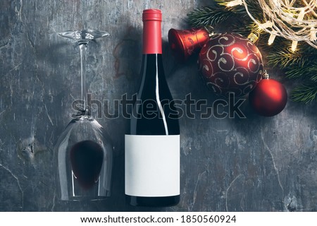 Top view of wineglass and bottle with white blank label with Christmas decorations on dark background. Wine bottle mockup with glass of wine.