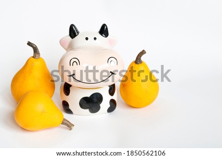 Three orange pumpkins in the shape of a pear and a piggy Bank in the shape of a bull on a white background. Hello autumn. Autumn pumpkin harvest. Farm of cows and pumpkins. New year of the bull