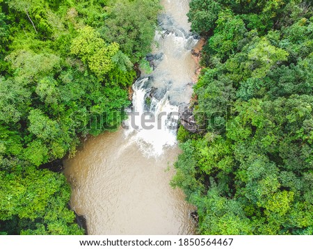 Aerial top view perspective of waterfall in tropical rainforest.