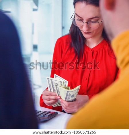 Metaphors photo of young business people holding money and analyzing financial balance of company. Stock market, office, tax, concept. Close up.
