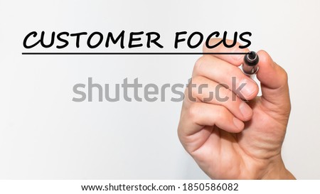the hand writes text CUSTOMER FOCUS with a marker on a white background. business concept