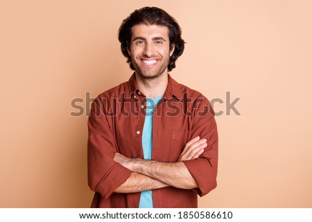 Photo of self-assured guy toothy smile look camera folded arms wear brown t-shirt isolated beige color background