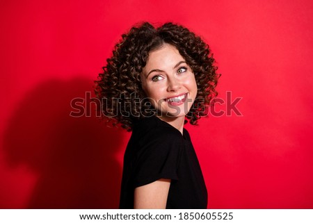 Photo portrait of smiling woman looking behind shoulder isolated on vivid red colored background