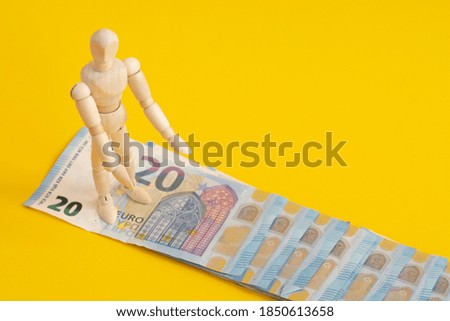 wooden figure of a man walking on Euro banknotes. Money