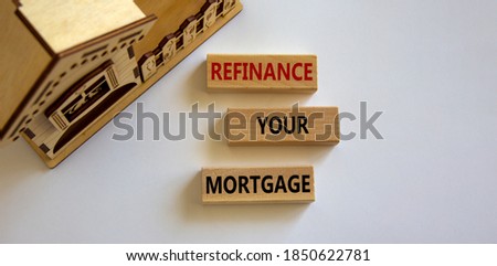 Wooden block form the words 'refinance your mortgage' near miniature house. Beautiful white background, copy space.