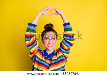 Photo of adorable young lady make hands look heart shape above head isolated on shine yellow color background