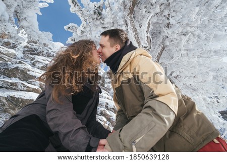Love couple of snowboarders outdoors in beautiful winter landscape under snow covered spruce trees, sunny winter day 