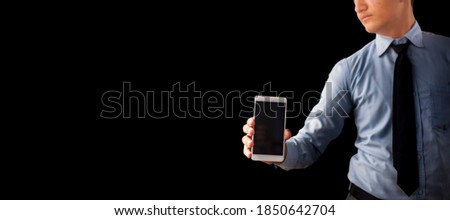 Shot of a well dressed employee holding an smartphone in his hand isolated on black background.