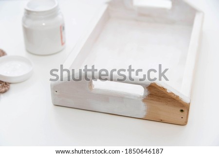Painting the wooden tray white. Home creativity concept.