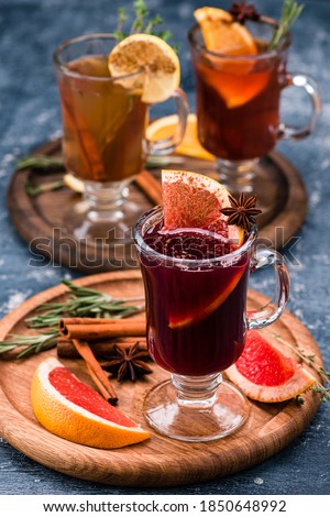Various autumn or winter seasonal alcohol hot cocktails - mulled wine, grog, warm ginger ale, hot rum, punch, mulled apple cider on gray background copy space