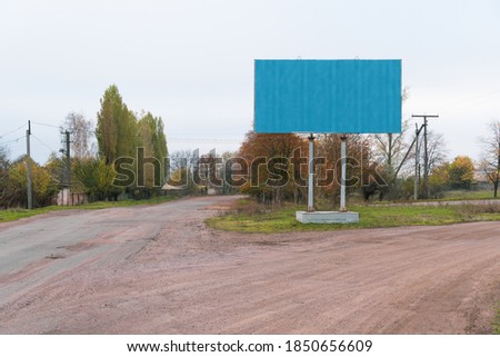 Blue blank billboard on the background of the road and gloomy sky