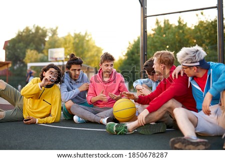caucasian teens, basketball players sitting and resting in timeout, enjoying outdoor games, happy youth lifestyle. in city